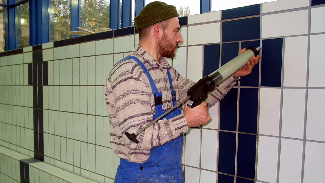 Grouting the tiles in the pool with a spray gun